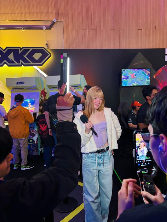 Steph de repórter, com microfone, gravando na Runeterra Fanfest